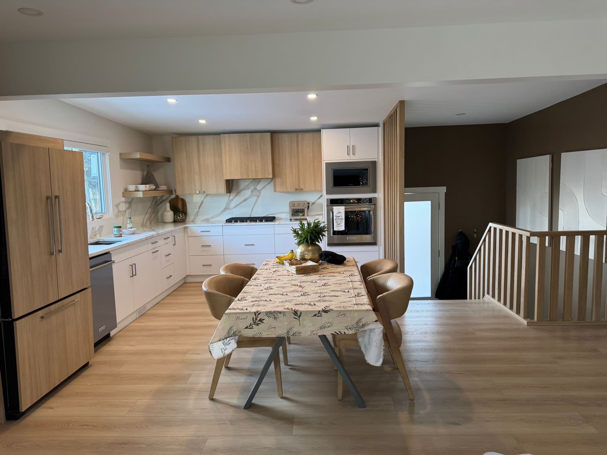 Finished modern kitchen with light wood paneled refrigerator, white lower custom cabinets, and light wood upper custom cabinetry, showcasing Calgary custom cabinets.